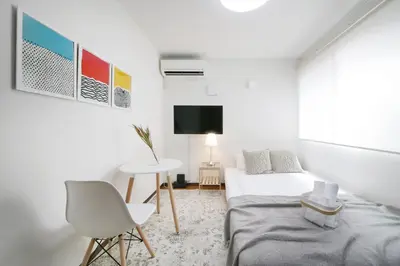 a white room with a bed and a table and a tv at \u30a2\u30ea\u30a2\u66f3\u821f in Tokyo