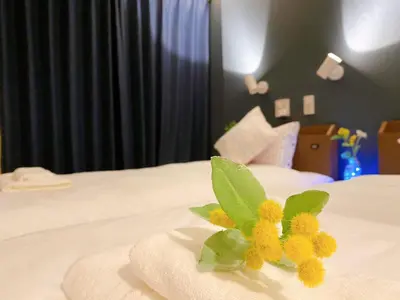 a yellow flower on top of a white bed at nestay villa tokyo akihabara in Tokyo