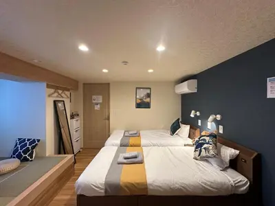 a bedroom with two beds and a blue wall at nestay villa tokyo akihabara in Tokyo