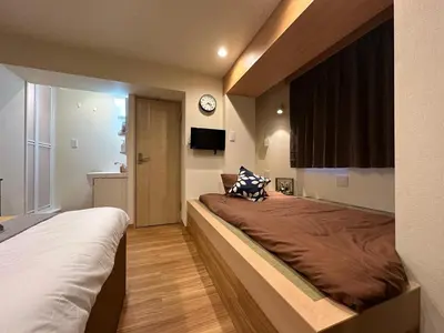 a bedroom with two beds and a clock on the wall at nestay villa tokyo akihabara in Tokyo