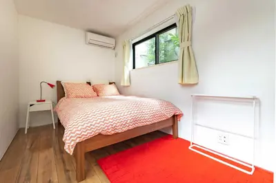 a bedroom with a bed with a window and a red rug at Pencil House - 10 mins walk to Shinjuku in Tokyo