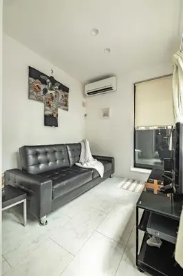 a living room with a black leather couch at Pencil House - 10 mins walk to Shinjuku in Tokyo