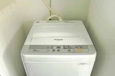 a white washing machine in a corner of a room at Pencil House - 10 mins walk to Shinjuku in Tokyo
