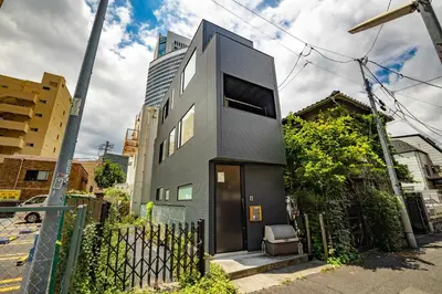a black house with a black door on a street at Pencil House - 10 mins walk to Shinjuku in Tokyo