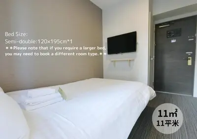a bedroom with two beds and a tv on the wall at The Light Inn Tokyo in Tokyo