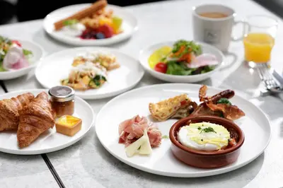 a table with plates of breakfast foods and a cup of coffee at AC Hotel by Marriott Tokyo Ginza in Tokyo