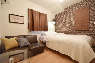 a bedroom with a bed and a couch and a brick wall at Hikifune Kodate - Vacation STAY 8861 in Tokyo