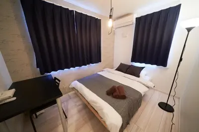 a bedroom with a bed with black curtains and a desk at Kitaikebukuro Kodate - Vacation STAY 8854 in Tokyo