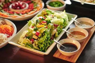 a table topped with plates of food with salad and dips at Sotetsu Fresa Inn Kanda-Otemachi in Tokyo