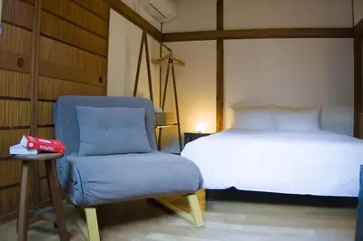 a bedroom with a bed and a chair next to a bed at Ikebukuro Nigo in Tokyo