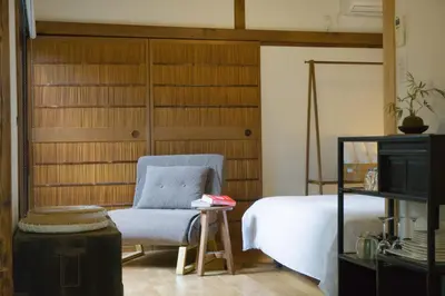 a bedroom with a bed and a chair and a tv at Ikebukuro Nigo in Tokyo