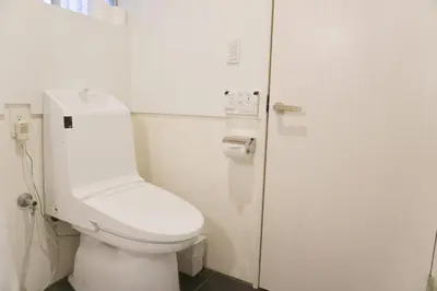 a bathroom with a white toilet and a door at Ikebukuro Nigo in Tokyo