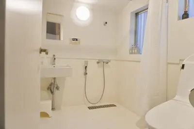 a white bathroom with a shower and a sink at Ikebukuro Nigo in Tokyo