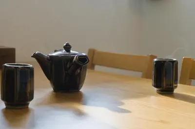 a black tea pot sitting on top of a wooden table at Nishibi in Tokyo