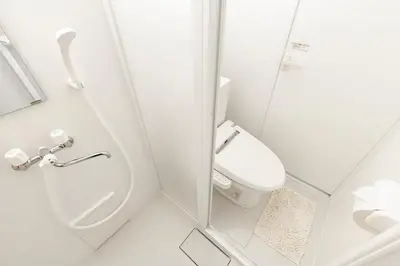 a white bathroom with a toilet and a shower at Port House Hatsudai in Tokyo