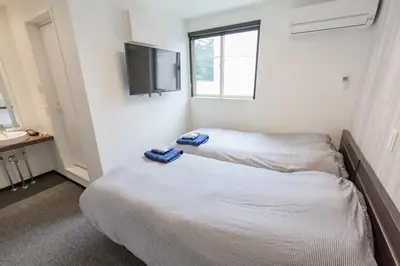 a bedroom with two beds and a flat screen tv at Port House Hatsudai in Tokyo