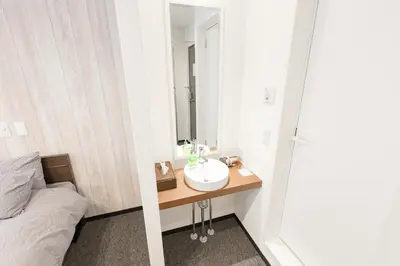 a bathroom with a sink and a bed and a mirror at Port House Hatsudai in Tokyo