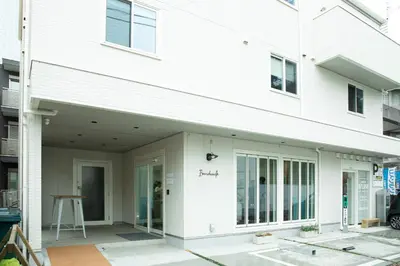 a white house with a front porch and a building at Port House Hatsudai in Tokyo
