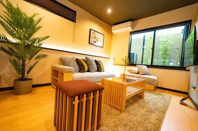 a living room with a couch and a palm tree at EAST ONE Higashishinjuku in Tokyo