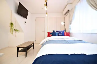 a bedroom with a blue and white bed and a table at R-Guest Residence \u6771\u4eac\u6d45\u8349 east2 in Tokyo