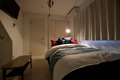 a bedroom with a bed with a bench and a window at R-Guest Residence \u6771\u4eac\u6d45\u8349 east2 in Tokyo