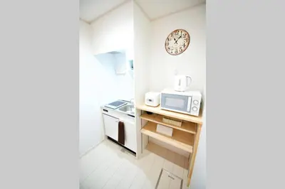 a small kitchen with a microwave and a clock on the wall at R-Guest Residence \u6771\u4eac\u6d45\u8349 east2 in Tokyo