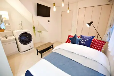 a bedroom with a bed and a washing machine at R-Guest Residence \u6771\u4eac\u6d45\u8349 east2 in Tokyo