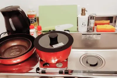 a red pot sitting on a stove next to a microwave at \u30d4\u30e9\u30cd\u30cf\u30a6\u30b9 in Tokyo