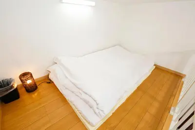 a bed in a room with a lamp on a wooden floor at Tokyo Enjoy Hotel in Tokyo