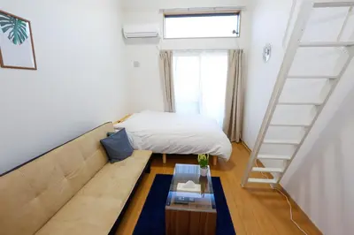a living room with a couch and a bed at Tokyo Enjoy Hotel in Tokyo