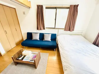 a small room with a bed and a blue couch at Tokyo Enjoy Hotel in Tokyo