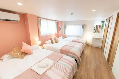 two beds in a room with pink walls and wooden floors at TK Court Ojima - Vacation STAY 91237 in Tokyo