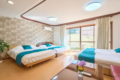 two beds in a room with a window at ColorBee Shinjuku Yotsuya Big House in Tokyo