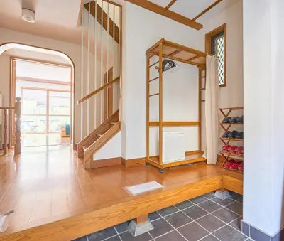 a living room with a staircase and a room with shoes at ColorBee Shinjuku Yotsuya Big House in Tokyo