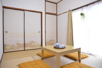 a living room with a table and large windows at Green House 101 in Tokyo