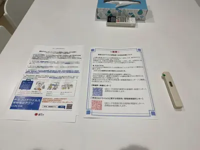 two papers on a white table with a remote control at Sunstay - Shinbamba 1 in Tokyo