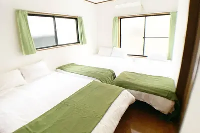 two beds in a bedroom with two windows at Sun Stay \u5927\u5d0e1 in Tokyo