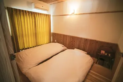 a small bedroom with a bed and a yellow curtain at morino yume private lodging Wood-warm cozy stays \u675c\u30ce\u5922 \u6c11\u6cca \u6728\u306e\u9999\u308a\u6f02\u3046\u5fc3\u5730\u3088\u3044\u7a7a\u9593 in Tokyo