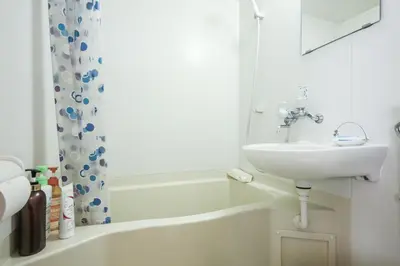 a white bathroom with a sink and a bath tub at Fuji House West Shinjuku in Tokyo