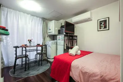 a bedroom with a bed and a table with a red blanket at North Cottage Studio Apartment with private entrance in Tokyo