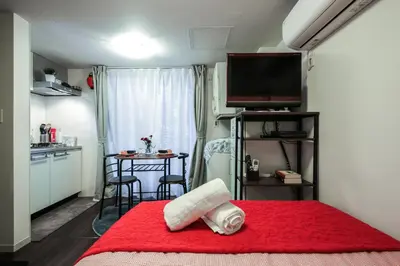 a small room with a red bed and a kitchen at North Cottage Studio Apartment with private entrance in Tokyo