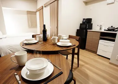 a room with a table with plates and a bottle of wine at Prime Suites Tokyo in Tokyo