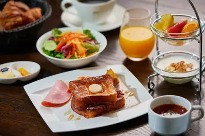 a table with a plate of food and a salad and orange juice at The Gate Hotel Kaminarimon by Hulic in Tokyo