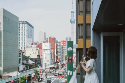 a woman taking a picture of a city street at The Gate Hotel Kaminarimon by Hulic in Tokyo