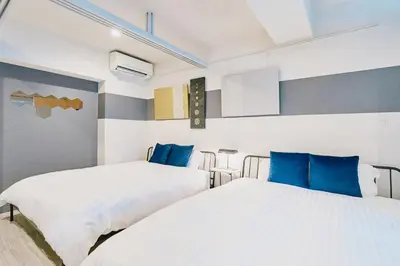 two beds in a room with blue pillows at Sukumo -\u8485- in Tokyo