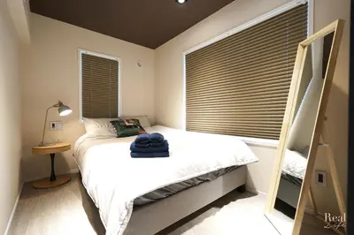 a bedroom with a bed and a window with blinds at Real Life AOYAMA in Tokyo