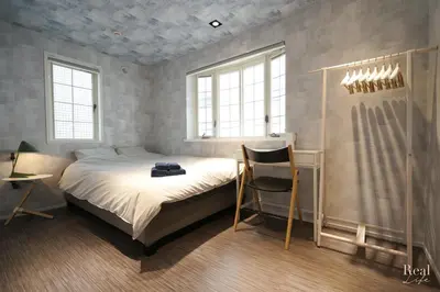 a bedroom with a bed with a chair and windows at Real Life AOYAMA in Tokyo