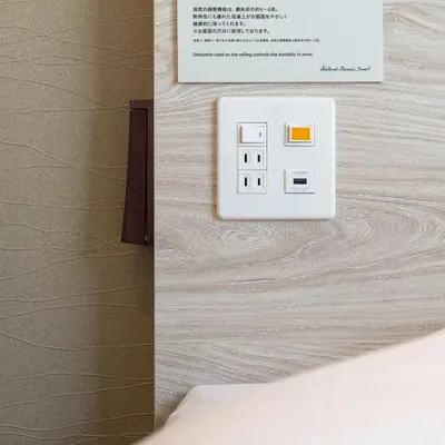 a light switch on a wall next to a bed at Super Hotel Tokyo Akabane Eki Minamiguchi in Tokyo