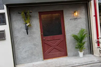 a red door on the side of a building with a plant at Exclusive Accommodation 9bicycle 9ppl in Tokyo