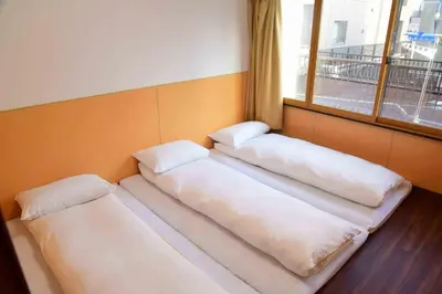three beds in a room with a window at \u4e0a\u91ce\u4e4b\u5bb6Vip\u5bb6\u5ead\u623f in Tokyo